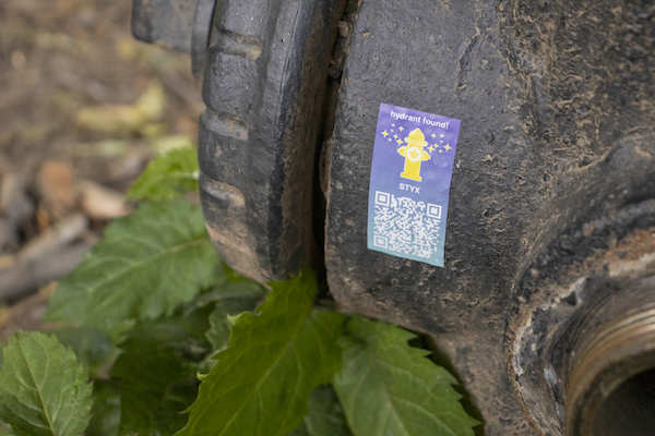 Fire hydrant with a colorful sticker on it. The sticker contains a QR code.